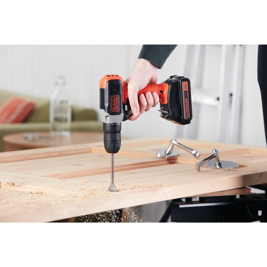 20 volt MAX cordless drill driver being used by a person to carve wood.