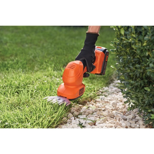 20 volt MAX shear shrubber being used by a person to trim grass.