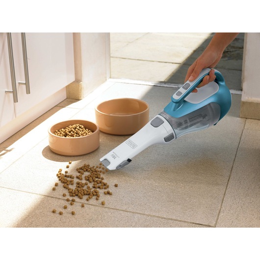 dust buster Hand Vacuum being used to pick pet food from floor.