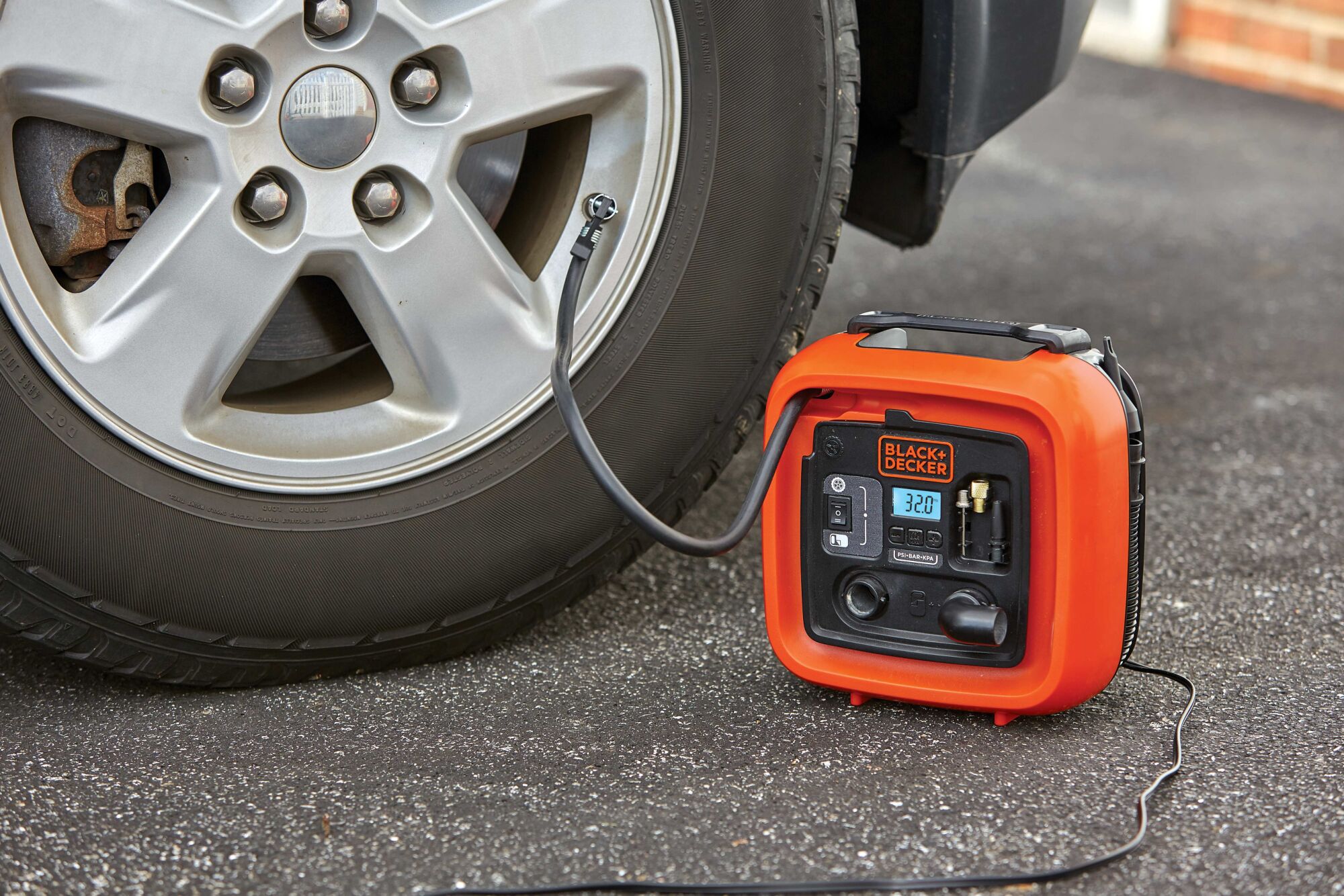 12 volt D C multi purpose inflator being used to inflate car tire.