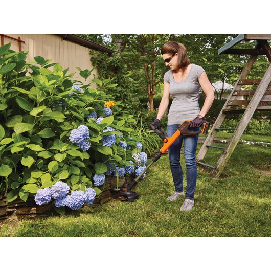 20 Volt Lithium EASY FEED String Trimmer Edger plus 2 Lithium Ion Batteries being used by a person in a garden.